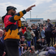 Christian Smalls speaks into a microphone with arm raised amid a crowd of people in front of a large Amazon sign.